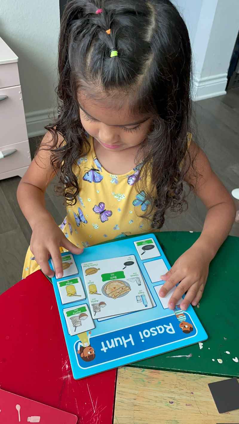 Young child placing ingredients on player board to make roti while playing Rasoi Hunt game made by Play N Seekh. 